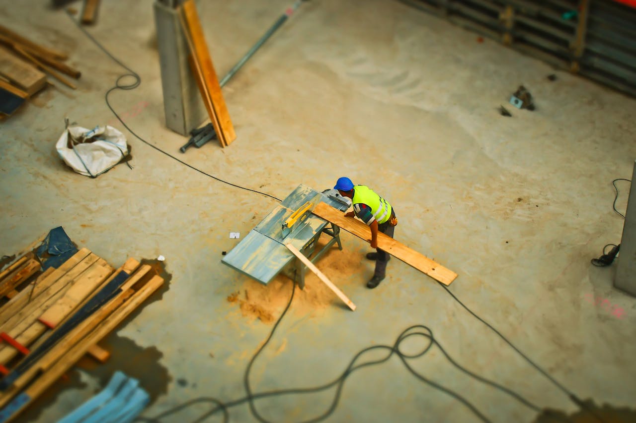 Overhead view of a construction worker using a saw to cut wood at a construction site.