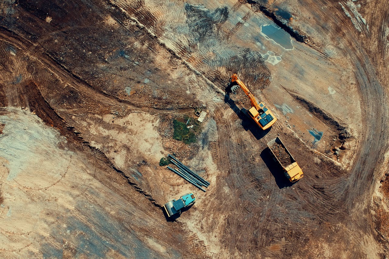 Aerial view of a construction site featuring heavy machinery and trucks, displaying industrial activity.