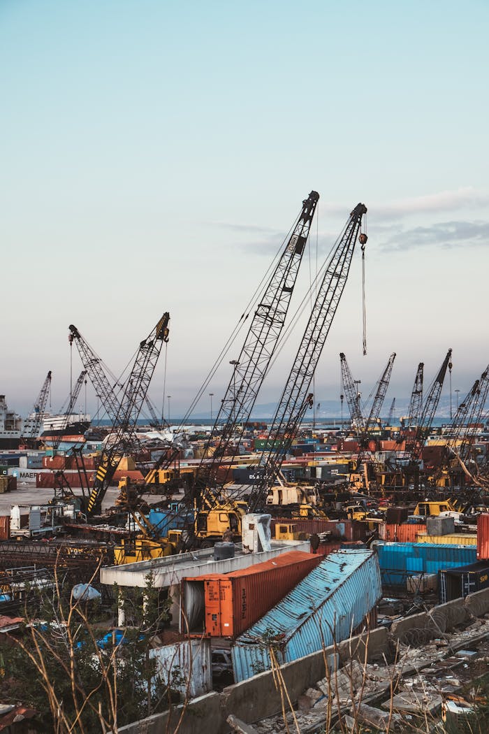 Cranes and shipping containers at Beirut port during sunset, showcasing industrial activity.